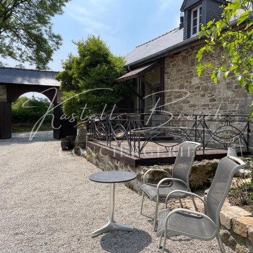 two chairs and a table in front of a building at Le Cocon du manoir de Kerollivier in Saint-Gilles-Pligeaux