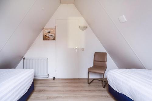 a attic bedroom with two beds and a chair at Kuifeend I Chalet met Modern Interieur in Zwiggelte