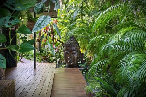 a wooden walkway with a statue in a garden at The Palms At Palm Cove in Palm Cove