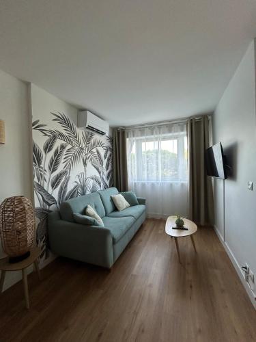 a living room with a blue couch and a wall at Appartement proche plage, CARNON in Mauguio