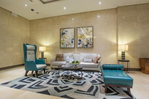 ein Wohnzimmer mit einem Sofa und zwei blauen Stühlen in der Unterkunft Cozy Home at Venice Luxury BGC in Manila