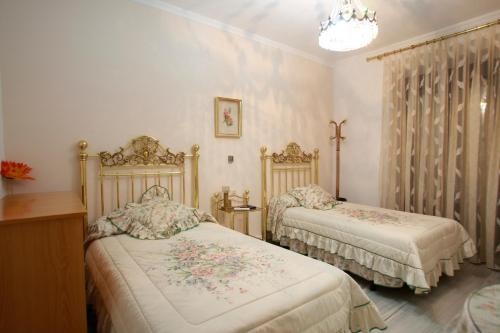 1 dormitorio con 2 camas y lámpara de araña en Hostal Jiménez, en Azuaga