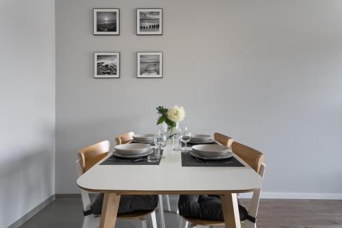 a white dining room table with chairs and a white wall at Symphony Baltica Towers Apartamenty in Gdańsk