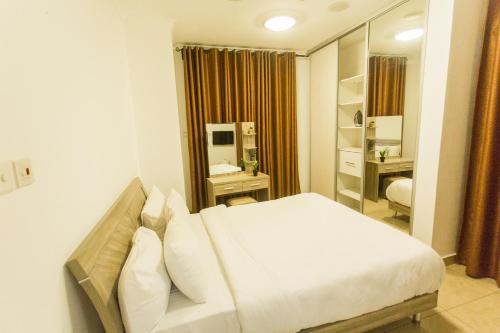 a bedroom with a white bed and a mirror at Accra Luxury Apartments at Avant Garde in Accra