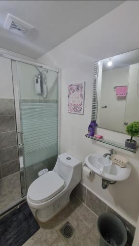 a bathroom with a toilet and a sink and a shower at Joms Cozy Staycation in Calamba