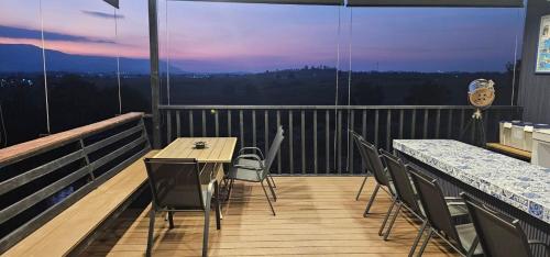 a balcony with tables and chairs and a view at Black Sheep House Khaoyai by ALPHATEL PARTNER in Pong Talong