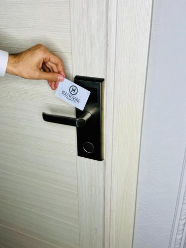 a person holding a door handle with a card at South Hotel Tashkent in Tashkent