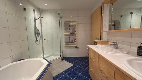 Un baño con bañera y dos lavabos y ducha. en Ferienwohnung Nardin, en Mellau