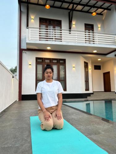 a man sitting on a yoga mat in front of a house at Villa Elegant Oasis in Horana