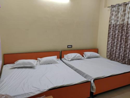 two beds in a room with white sheets and pillows at Geeta Teerth Guest House AC and Non AC Rooms in Ayodhya