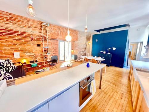 Il dispose d'une cuisine et d'un salon avec un mur en briques. dans l'établissement Mon bout de Garonne - Appartement 2 CH - Garonne, à Toulouse
