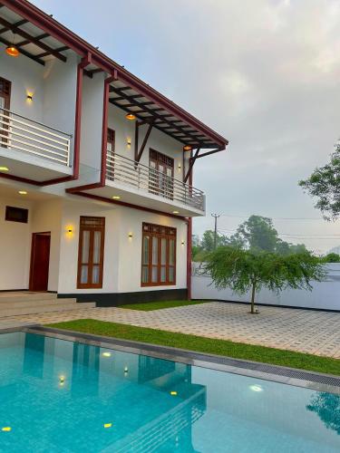 a house with a swimming pool in front of it at Villa Elegant Oasis in Horana