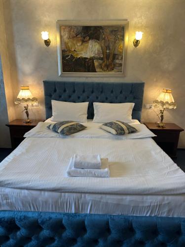 a large white bed with a blue headboard and two lamps at Vila Royal in Bacău