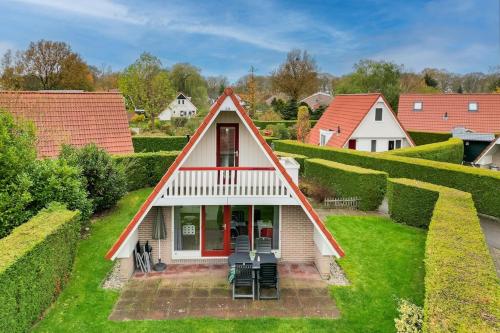a small house with a red roof at Gele Kwikstaart I Ruime Woning met Omliggende Tuin in Zwiggelte