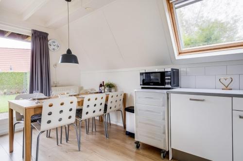 a kitchen with a table and chairs and a microwave at Gele Kwikstaart I Ruime Woning met Omliggende Tuin in Zwiggelte