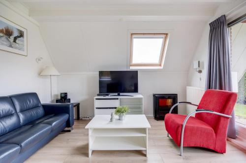 a living room with a couch and a tv at Gele Kwikstaart I Ruime Woning met Omliggende Tuin in Zwiggelte