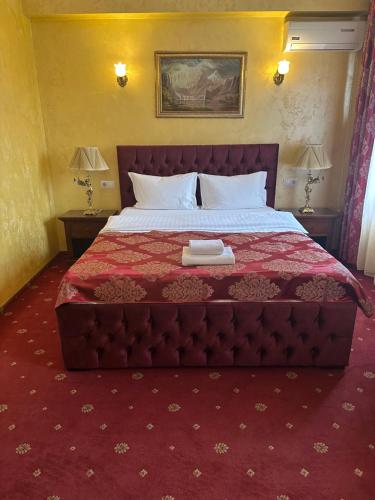 a bedroom with a large bed with a red comforter at Vila Royal in Bacău