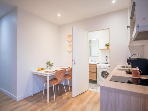 Il comprend une cuisine avec une petite table et des murs blancs. dans l'établissement Le Cosy Express, à Villefranche-sur-Saône