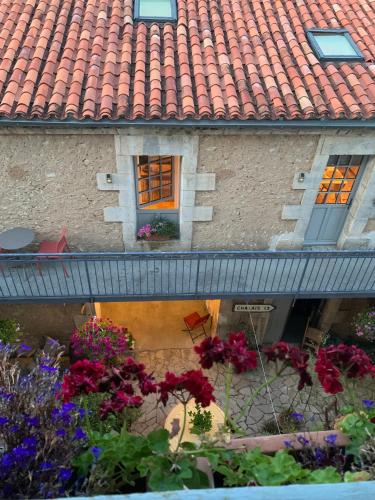 a building with a tile roof with flowers in front of it at Repos à Ribérac B&B in Ribérac
