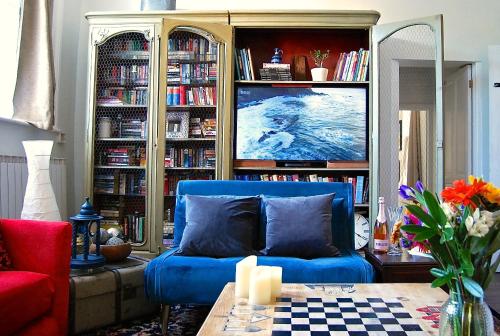 a living room with a blue couch and a book shelf at Hampton Court Snug Walk to train & palace in East Molesey