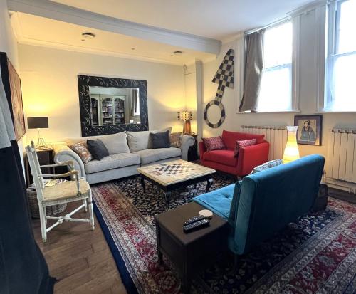 a living room with a blue couch and red chairs at Hampton Court Snug Walk to train & palace in East Molesey