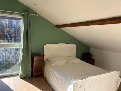 une chambre avec un lit blanc et une fenêtre dans l'établissement La loge des ânes, à Naucelles
