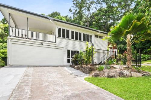a house with a garage and a palm tree at The Residence- Rainforest Retreat in Stratford