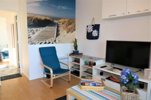 un salon avec une chaise bleue et une télévision dans l'établissement Bel appartement rénové avec jardin, VUE MER à PERROS-GUIREC - Réf 946, à Perros-Guirec