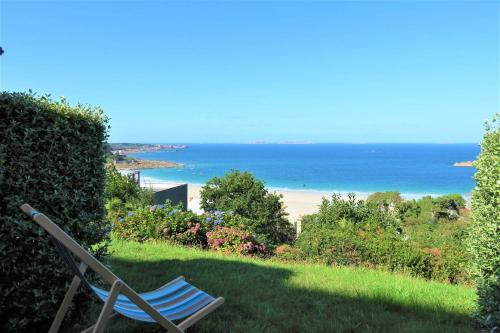 une chaise assise sur l'herbe près d'une plage dans l'établissement Bel appartement rénové avec jardin, VUE MER à PERROS-GUIREC - Réf 946, à Perros-Guirec