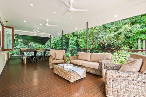 a screened in porch with wicker chairs and a table at The Residence- Rainforest Retreat in Stratford
