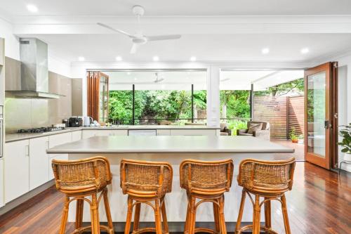a kitchen with a large island with four chairs at The Residence- Rainforest Retreat in Stratford
