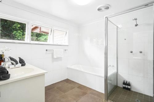 a white bathroom with a shower and a sink at The Residence- Rainforest Retreat in Stratford