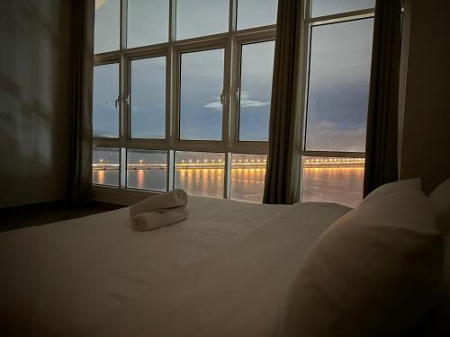 a white bed with a towel sitting on it in front of a window at Invincible Seaview Vacation Condo 3R3B 8Pax in Bayan Lepas
