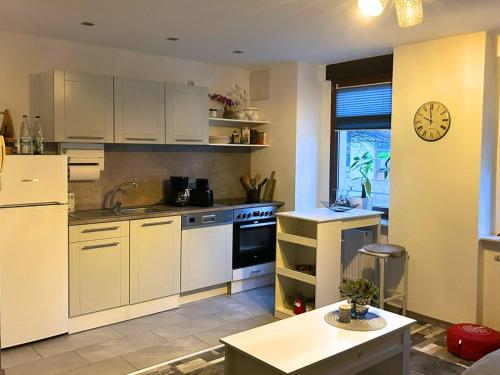 a kitchen with white cabinets and a clock on the wall at Ferienwohnung Musche in Bad Frankenhausen