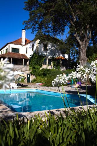 a swimming pool in front of a house at Lugar da Pedra Alta - B&B - Private Historical Villa in Melo