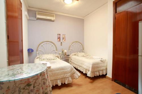 a room with two beds and a table at Hostal Jiménez in Azuaga