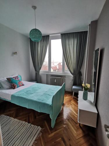 a bedroom with a bed and a large window at Апартамент Център in Vratsa
