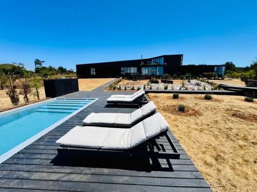 a swimming pool with lounge chairs next to a house at Vista al mar. Tunquen in Valparaíso