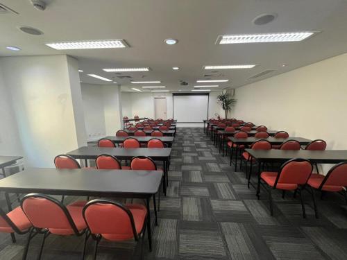 a lecture room with tables and red chairs at Intercity São Paulo Ibirapuera in Sao Paulo