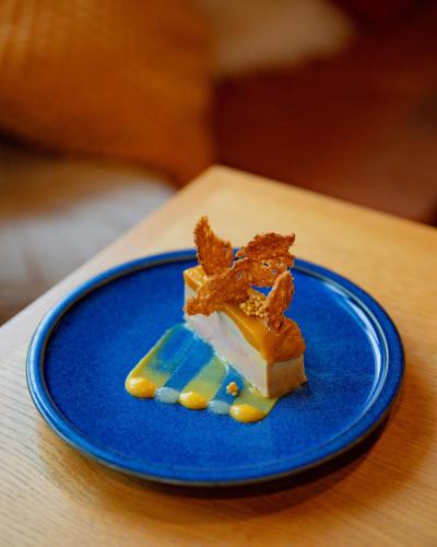 a piece of food on a blue plate on a table at ISKÖ CHALETS-HÖTEL, Col d'Aubisque in Gourette