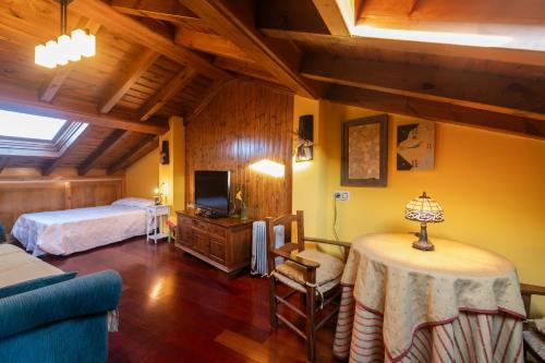 a room with two beds and a table and a tv at Villa El Retiro Un Alojamiento con Encanto in Mediavilla