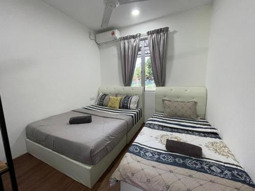 a bedroom with two beds and a window at Laman Hanaz - Homestay Aufa in Pantai Cenang