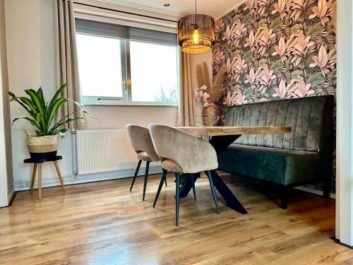 a dining room with a table and a green couch at Chambre d'hôtes 't Jagertje in Langweer