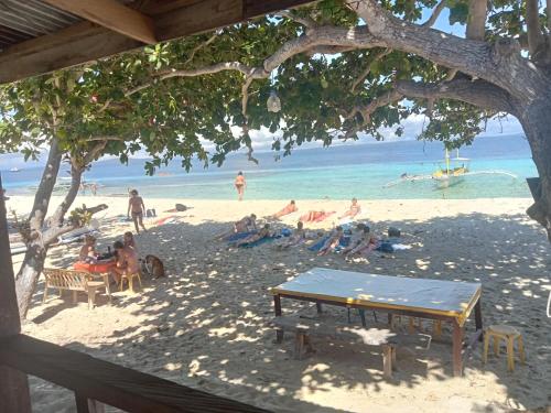 a group of people sitting on a beach at Enas cottages in Pamilacan IsLand in Baclayon