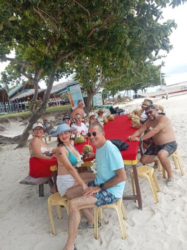 a group of people sitting at a table on the beach at Enas cottages in Pamilacan IsLand in Baclayon
