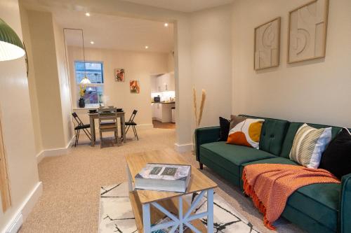 a living room with a green couch and a table at Stylish Gateway-2 bedroom house -5 minutes from the beach in Eastbourne
