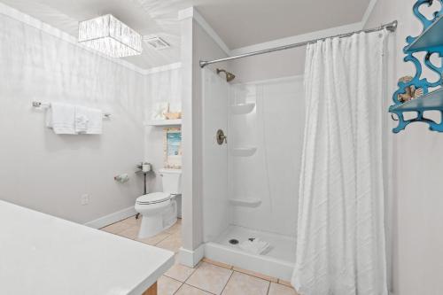 a white bathroom with a shower and a toilet at Beach House - Leaf Relief by Panhandle Getaways in Port Saint Joe