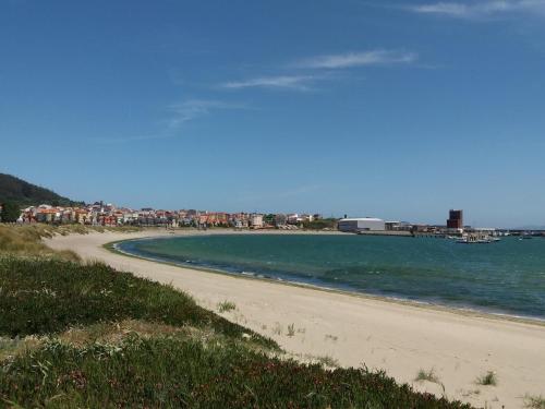 a sandy beach with buildings in the background at Paraíso Ortegal in Feás