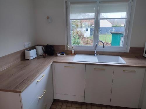 une cuisine avec un évier et une fenêtre dans l'établissement Cottage Stelie, à Tocqueville-en-Caux