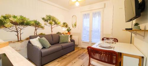 a living room with a couch and a table at A L'ombre des Pins, Appartement neuf, élégant, Parking gratuit, Netflix, au calme à 100m de l'océan in Les Sables-dʼOlonne